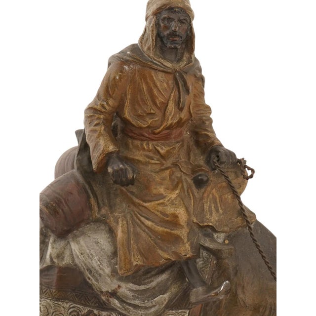 An antique Austrian cold-painted bronze sculpture depicting a Bedouin or Arab rider mounted on a camel, executed in the...