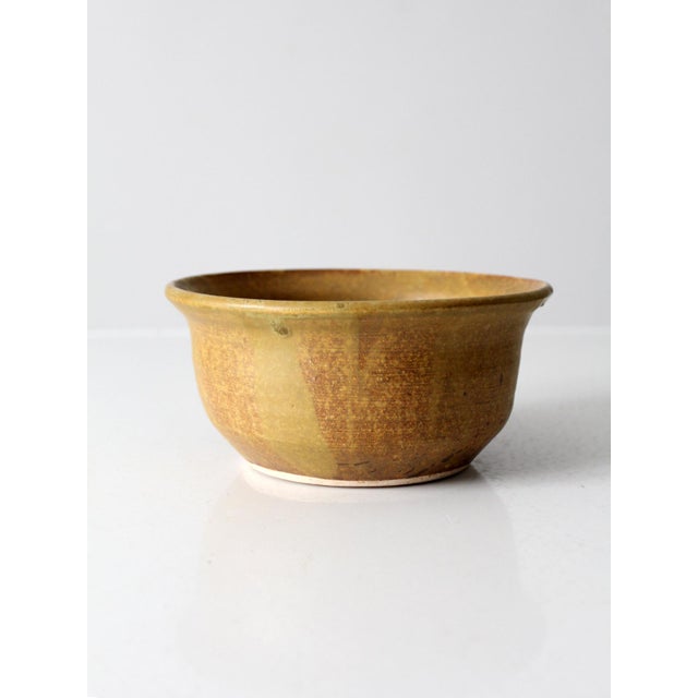 This vintage studio pottery bowl dates to the 1970s and features a warm ochre glaze with natural variation and a classic,...