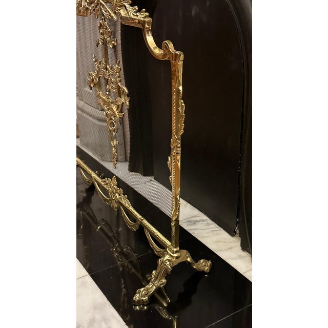 An antique fireplace screen in the Louis XVI style with Rococo elements. The brass frame features ribbons, leaves,...