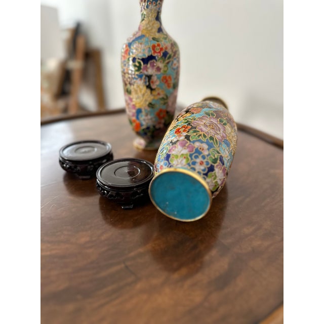 A pair of lovely cloisonné vases with carved wooden bases included. Very vibrant colors and very good condition.