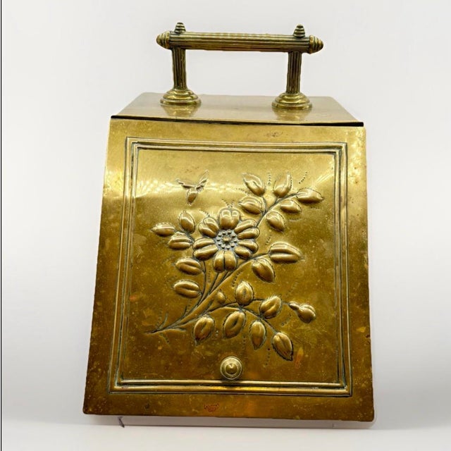 THE SKINNY Late Victorian–Edwardian brass coal scuttle with embossed floral and bee motif, raised bun feet, and...