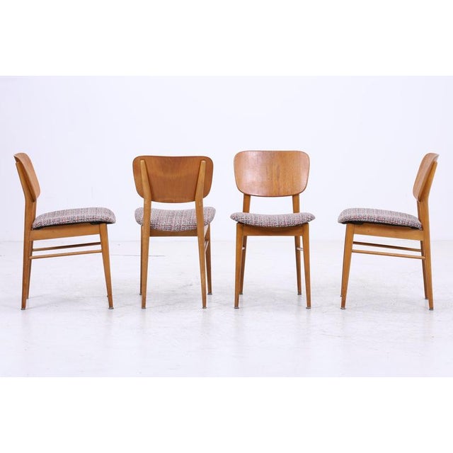 Set of four vintage dining chairs from the 1960s with clean lines and comfortable seating. The warm wood grain and newly...