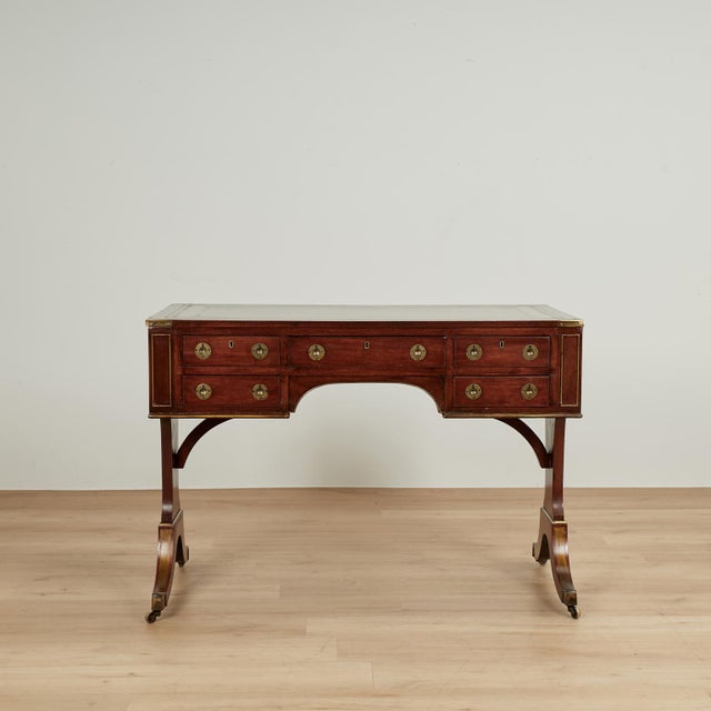 Handsome antique English desk crafted in mahogany with a tooled leather top on a case with five drawers and campaign style...