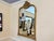 An elegant wall mirror featuring a gracefully shaped frame with a serpentine top, carved crest, and warm gilt finish. The...