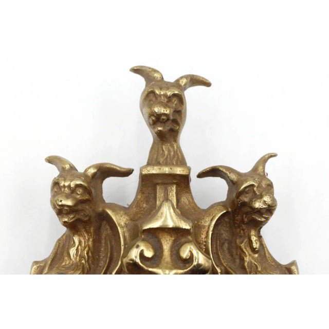Vintage brass door knocker featuring three stylized animal heads, which could be interpreted as Cerberus. The original...