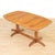 This elegant mid-century extending dining table features beautifully grained teak construction with a warm natural tone...