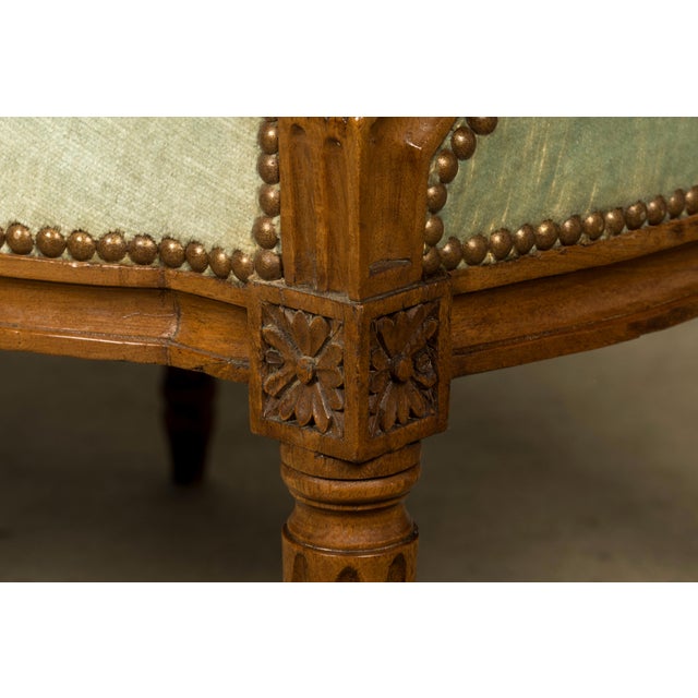 A late 18th-century French Louis XVI carved walnut settee, sourced in Loire Valley, France. Crafted in solid walnut, the...