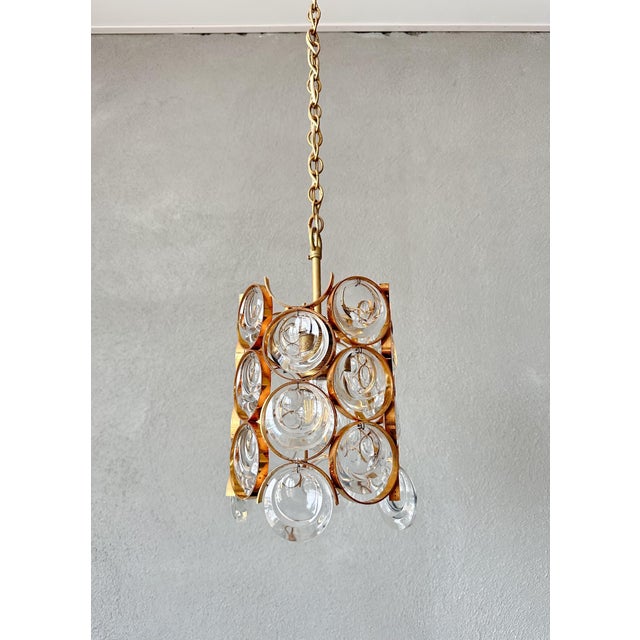 Elegant Palwa pendant lamp in a gold-colored frame with refined crystal glass. This compact yet luxurious lamp is known...