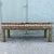 A glamorous vintage Hollywood Regency Parsons-style bench featuring richly layered upholstery in muted sage green, gold,...