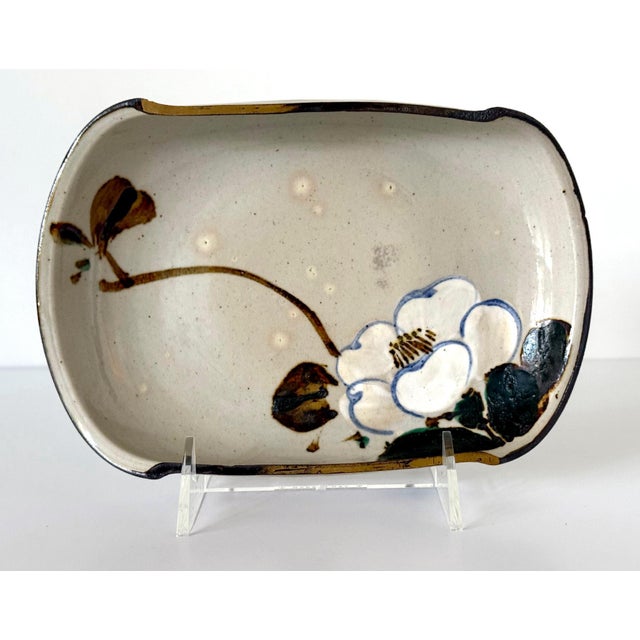 A glazed ceramic shallow bowl with surface paint decoration by Japanese imperial potter Makuzu Kozan ((1842–1916) with its...