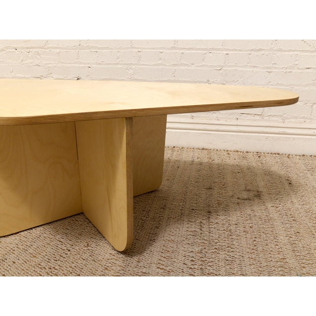 A beautifully sculptural coffee table with a bold postmodern silhouette and warm blonde wood finish. The asymmetrical top...