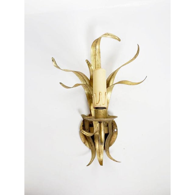 French decorative wall light dating from the 1970s, crafted from gilt metal. The design features an expressive arrangement...