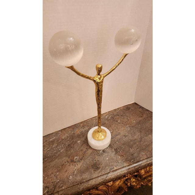 This listing features a brass figural sculpture balancing two selenite balls, on top of a marble circular base. Selenite...