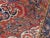 Central medallion flanked on both ends on a floral decorated red field. Border displaying stylized flowers. 100% pure wool...