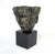 A Brutalist head sculpture with three faces at different angles sitting on a dark charcoal marble slab square base. The...