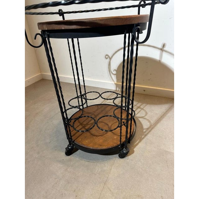 Charming vintage bar cart featuring a beautifully twisted wrought-iron frame paired with warm wooden shelves. The circular...