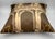 A decorative silk throw pillow featuring an architectural fantasy design in the style of Fornasetti, with classical...