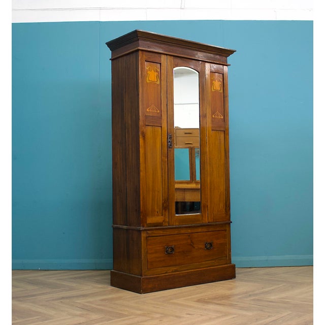 An Edwardian mahogany wardrobe or hall robe featuring a central mirrored door flanked by decorative Art Nouveau inlaid...