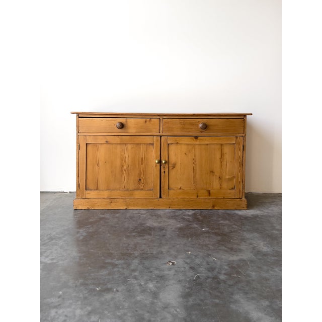 This antique English pine sideboard features a warm, rich honey-toned finish. Designed with two smooth sliding top drawers...