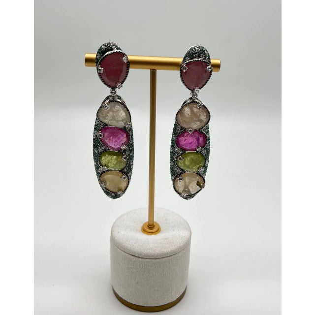 Earrings featuring multicolored sapphires set in a vertical arrangement of 57.23 carats. The top stone is a deep pink,...