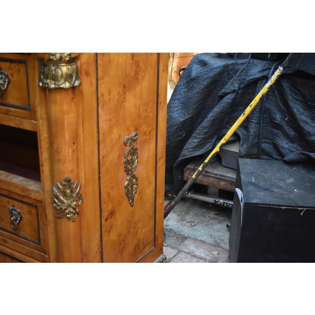 French Empire-style four-drawer commode crafted in burl walnut veneer with polished gilt-brass (ormolu) mounts. The piece...