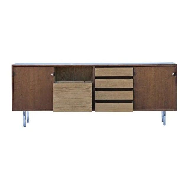 A classic and iconic mid century modern credenza designed by Florence Knoll for Knoll c. 1950s. A walnut case with...