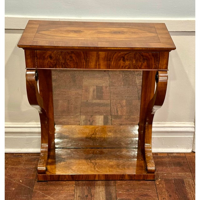 An elegant antique Biedermeier console table dating to the early 19th century, distinguished by richly figured walnut and...