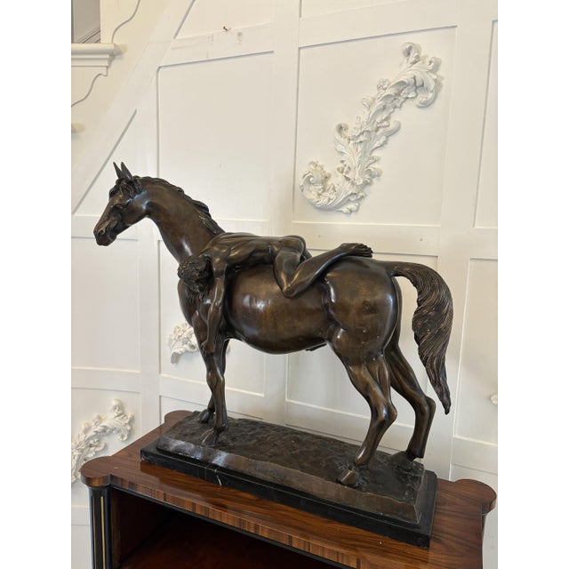 Large antique bronze study of a nude male on horseback having an unconscious man draped across the horse's back, the...