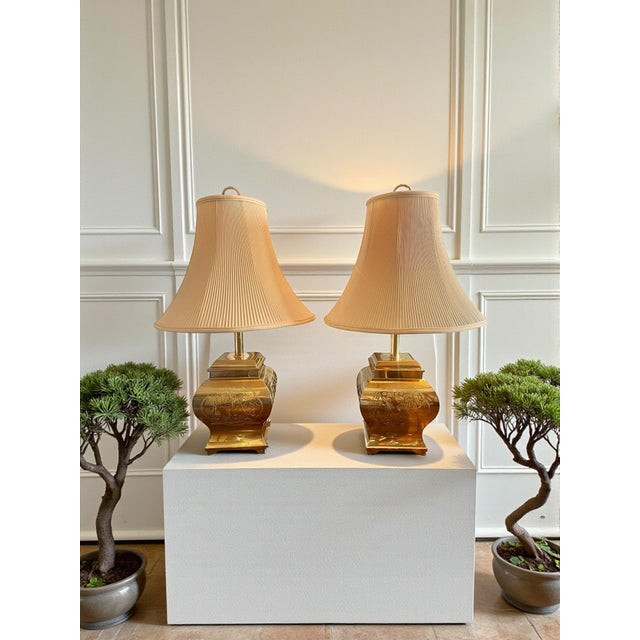 This elegant pair of vintage brass table lamps showcases finely engraved chinoiserie scenes, a decorative tradition...