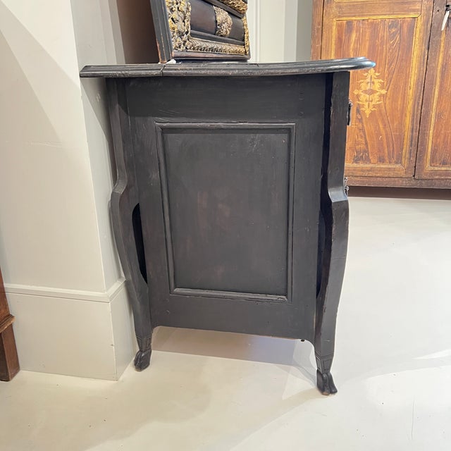 A striking 18th century French Mazarine chest finished in deep black, featuring elegant hoof feet and gleaming silver...