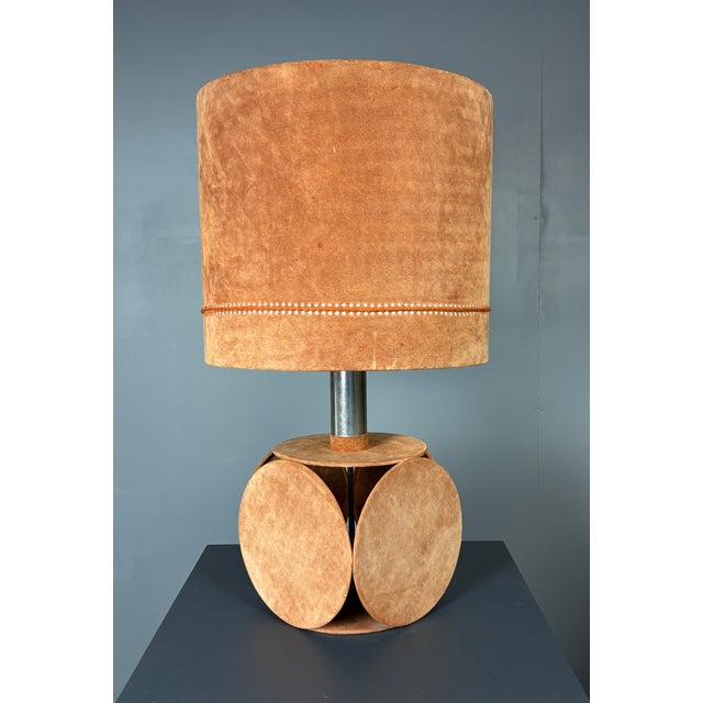 A substantial 1970s table lamp with a sculptural base constructed from suede-wrapped circular discs arranged around a...