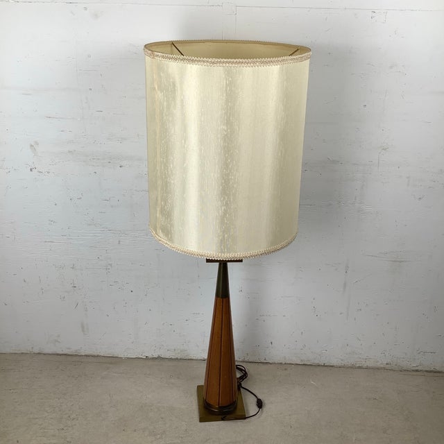 This striking mid-century modern table lamp showcases a beautifully tapered walnut cone base accented by a square brass...