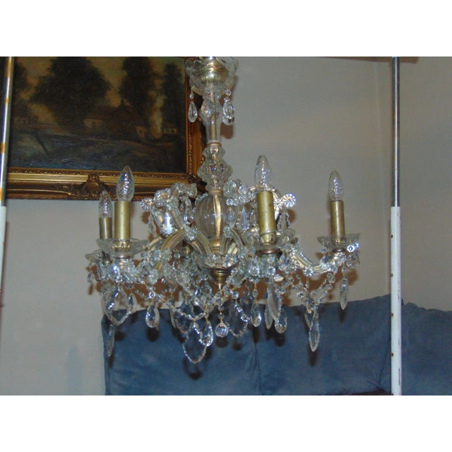 This chandelier is comprised of a brass under construction covered in crystal glass. The piece features six lights...