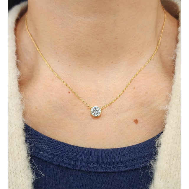 A refined 14k yellow gold necklace showcasing a single natural round-cut white diamond weighing 1.12 carats. The diamond,...