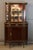 A louis xvi style mahogany display cabinet with rounded sides. The upper section features a slightly recessed glass-...