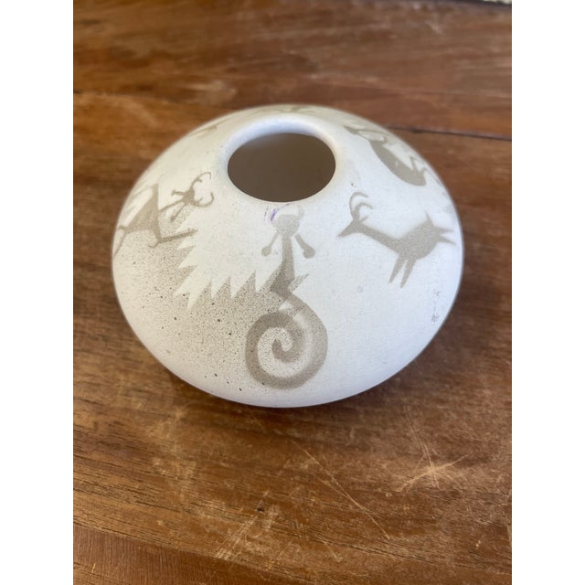 Vintage Hozoni Pottery ceramic vase featuring traditional Native American-inspired imagery. The vessel has a low, rounded,...