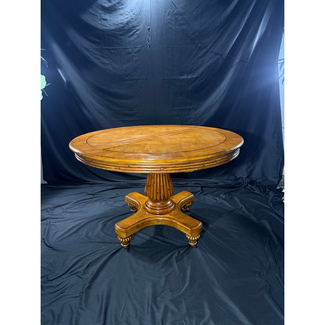 A striking vintage round dining table featuring a richly figured burl wood finish, decorative geometric inlay, and an...