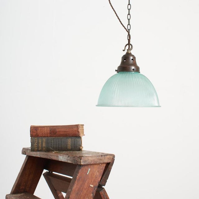 A vintage bell pendant glass light manufactured by ‘holophane’ in an unusual blue glass colour variation. The light has an...