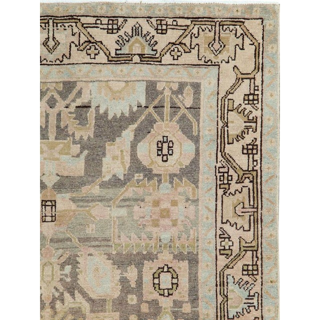 This mid-20th-century Persian Malayer rug presents a balanced geometric-floral composition in muted blue, ivory, beige,...