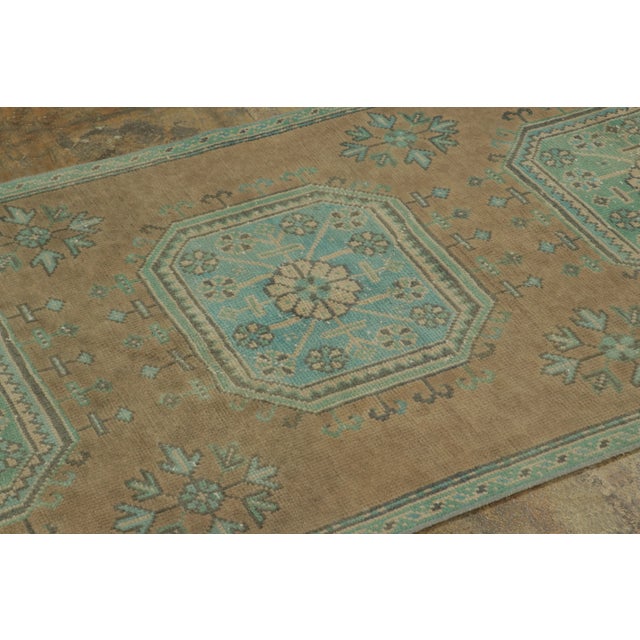 Hand-knotted in wool, this vintage 3x10 Turkish runner rug, circa 1950–1959 showcases floral medallions in soft aqua and...