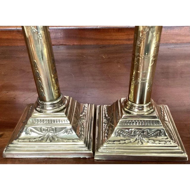Handsome pair of modern reproduction Classical style tall brass candlesticks. Sticks have foliage decoration of the shaft...