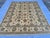 This elegant hand-knotted wool area rug features a classic Oushak style. The open center field has a warm cream background...