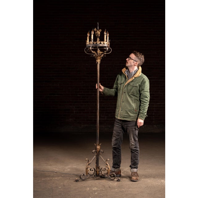 Tall wrought iron floor candelabra with dramatic Gothic Revival styling, featuring a slender central shaft rising from a...