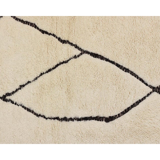 Minimalist hand-knotted wool rug in a soft Ivory hue, featuring flowing handwoven Charcoal lines that create a dynamic and...