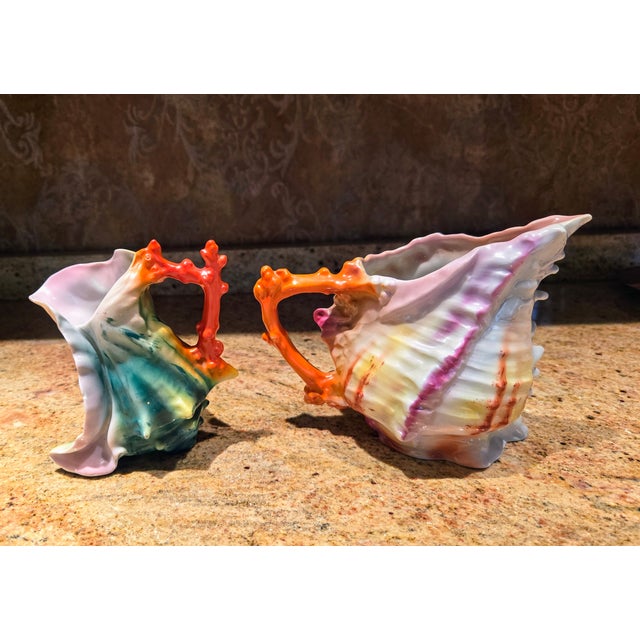 Includes Two porcelain creamers Made in Bavaria shaped like seashells with red coral handles. The creamers are hand...